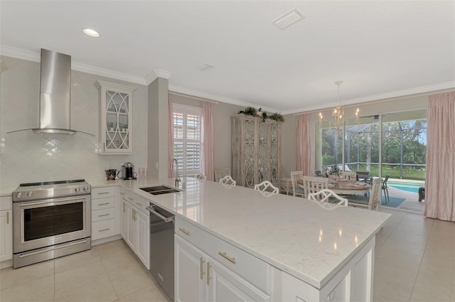 kitchen with wall chimney range hood, sink, stainless steel appliances, ornamental molding, and light tile patterned floors