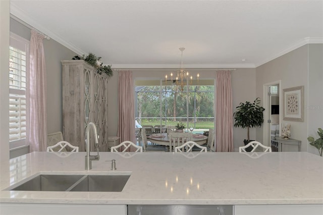 kitchen with pendant lighting, sink, crown molding, light stone countertops, and an island with sink