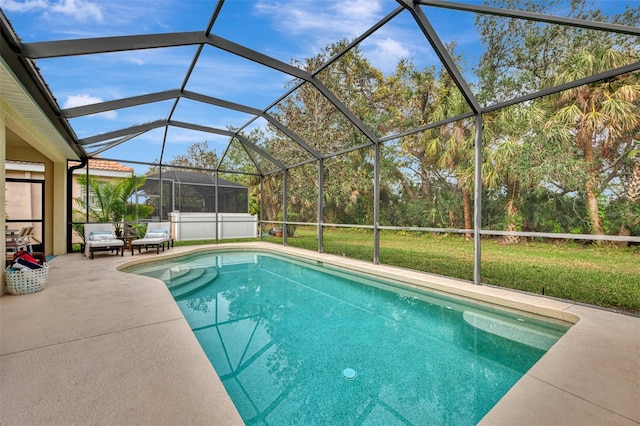 view of pool with glass enclosure, a yard, and a patio