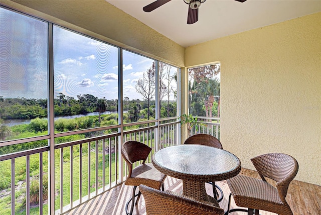 sunroom / solarium featuring a water view and ceiling fan