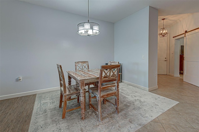 tiled dining room with a chandelier and a barn door