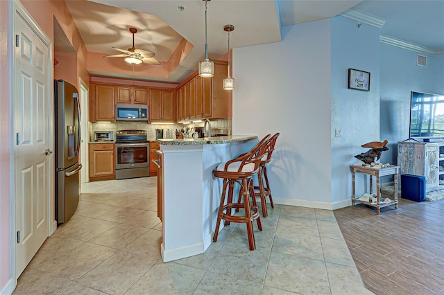 kitchen featuring decorative light fixtures, kitchen peninsula, a kitchen bar, crown molding, and stainless steel appliances