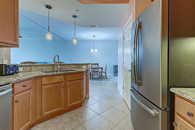 kitchen with decorative light fixtures, sink, light tile patterned flooring, light stone countertops, and stainless steel appliances