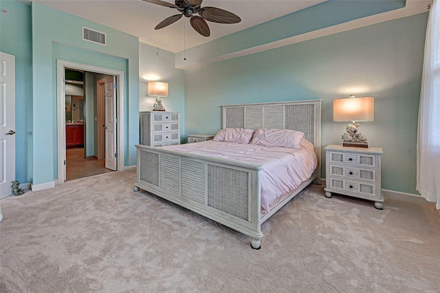 bedroom featuring ceiling fan, ensuite bath, and light carpet