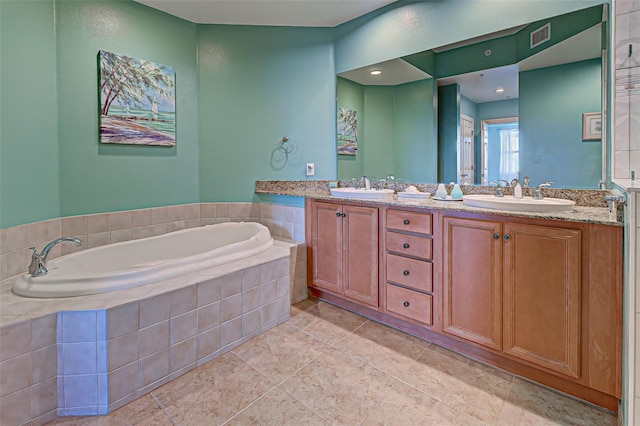 bathroom featuring tile patterned flooring, tiled tub, and vanity