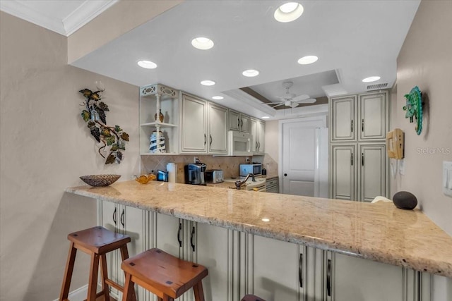 kitchen featuring crown molding, a breakfast bar, light stone counters, decorative backsplash, and kitchen peninsula