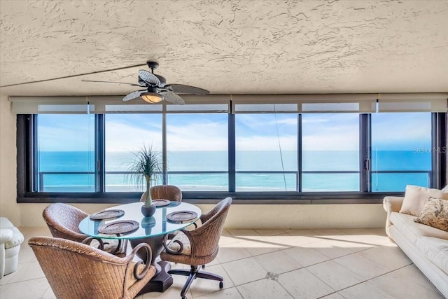 sunroom featuring a water view and ceiling fan