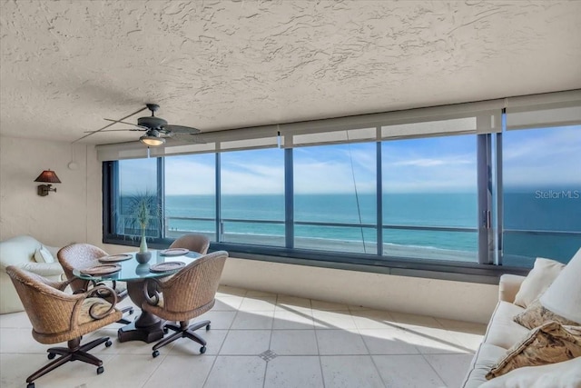 sunroom / solarium featuring a water view and ceiling fan