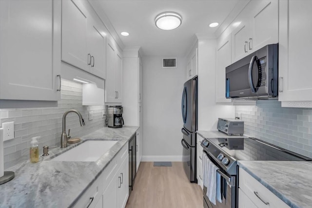 kitchen featuring white cabinets, light stone countertops, sink, and electric range