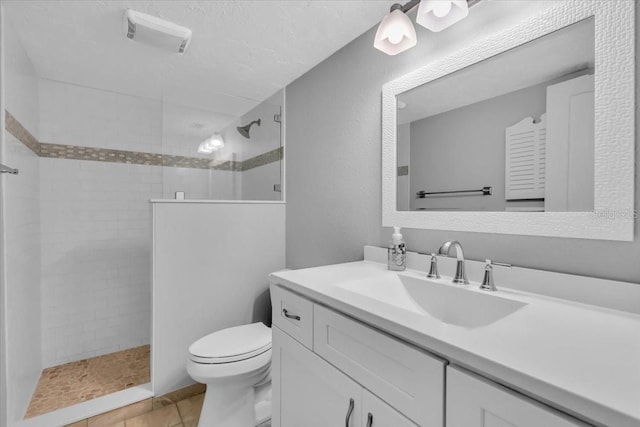 bathroom with vanity, tile patterned floors, toilet, and tiled shower