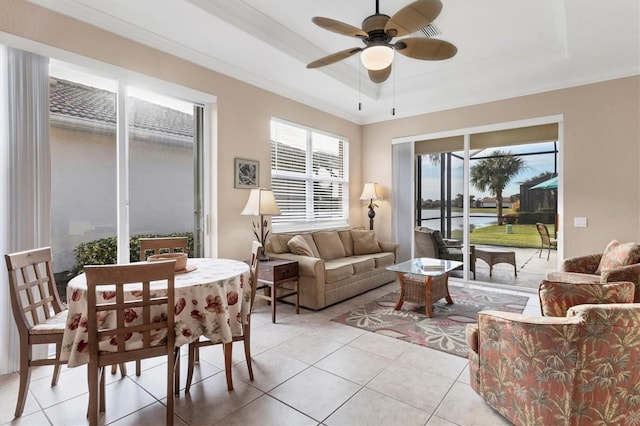 living room with light tile patterned floors, ceiling fan, a water view, ornamental molding, and a raised ceiling