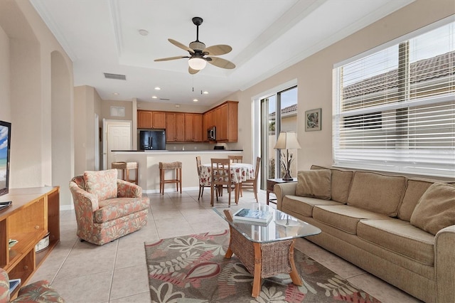 living room featuring light tile patterned floors, ceiling fan, and a tray ceiling