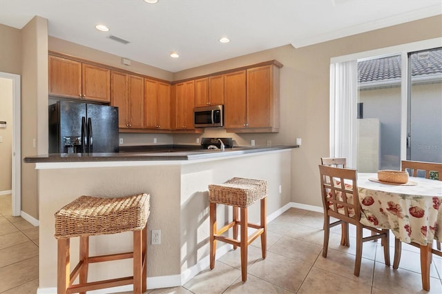 kitchen featuring kitchen peninsula, black refrigerator with ice dispenser, a breakfast bar area, and light tile patterned floors