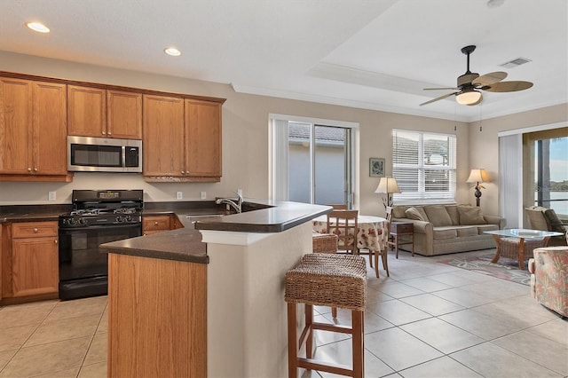 kitchen featuring sink, light tile patterned floors, a breakfast bar area, black gas stove, and ornamental molding