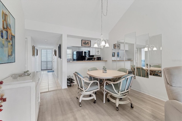 dining room with high vaulted ceiling, an inviting chandelier, and light hardwood / wood-style flooring