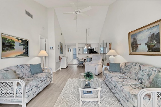 living room with high vaulted ceiling, ceiling fan with notable chandelier, and hardwood / wood-style floors