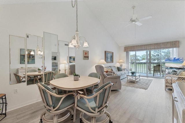 dining area with high vaulted ceiling, light hardwood / wood-style floors, and ceiling fan with notable chandelier