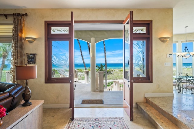 doorway to outside featuring a water view and an inviting chandelier