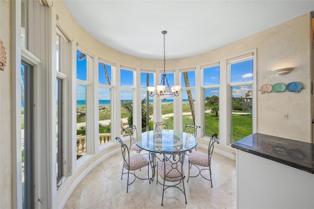 sunroom / solarium featuring an inviting chandelier and a water view