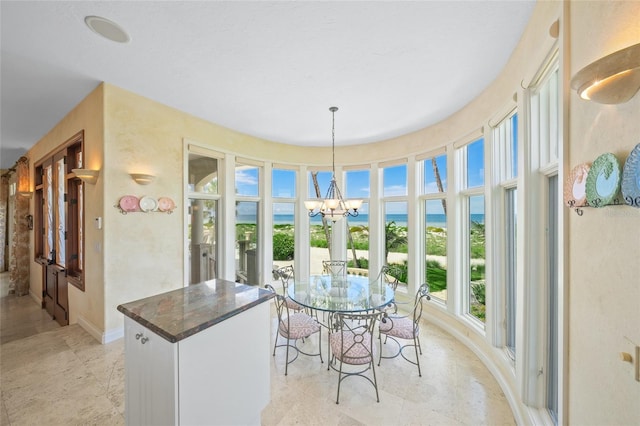 sunroom featuring a notable chandelier and a water view