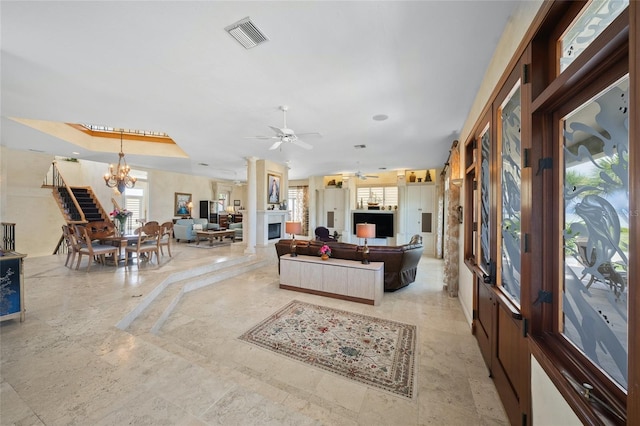 living room featuring ceiling fan with notable chandelier and a raised ceiling