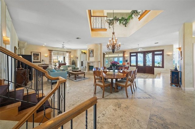 dining room featuring ceiling fan with notable chandelier, plenty of natural light, and a fireplace