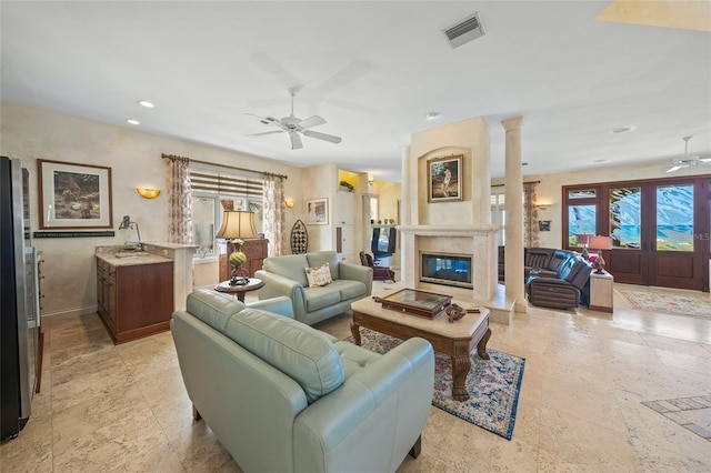 living room with ceiling fan, a wealth of natural light, a high end fireplace, and ornate columns