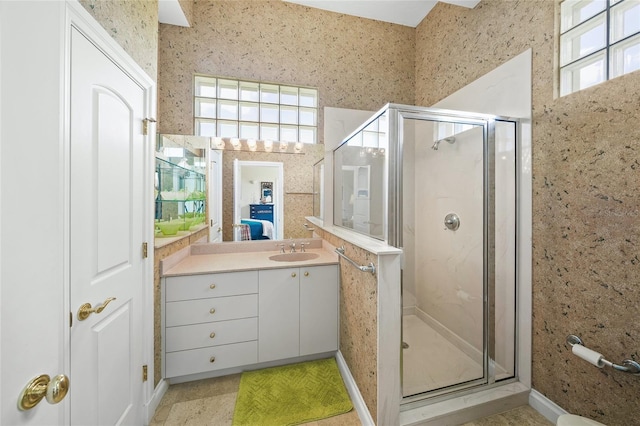 bathroom with a shower with shower door, a wealth of natural light, and vanity