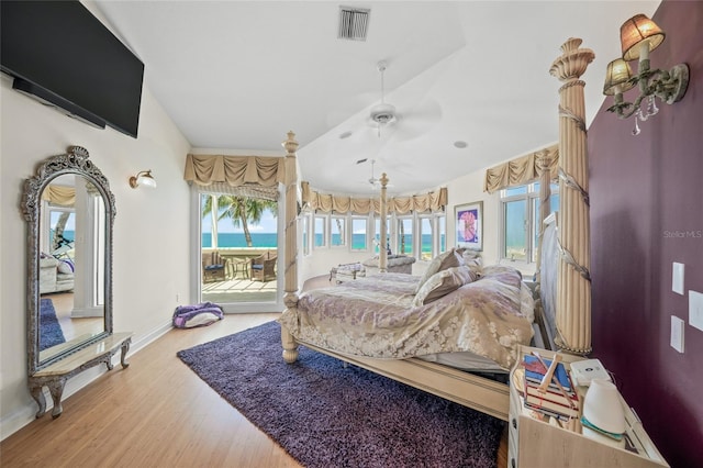 bedroom with ceiling fan, access to exterior, multiple windows, and a water view