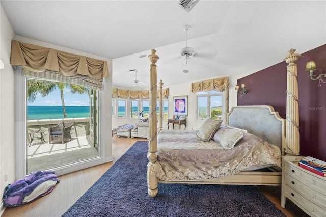 bedroom with access to exterior, light hardwood / wood-style floors, a water view, and ceiling fan