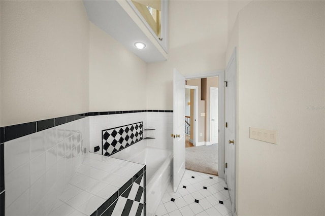 bathroom with tile walls, tile patterned flooring, and a bathing tub