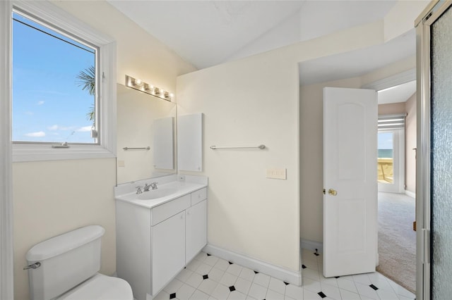 bathroom featuring toilet, vaulted ceiling, a wealth of natural light, and vanity