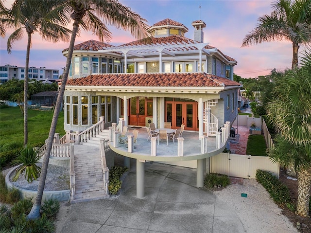 back house at dusk with a patio, a pergola, and french doors