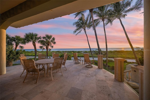 patio terrace at dusk with a water view and a beach view