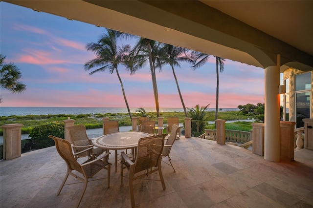 patio terrace at dusk featuring a water view