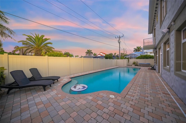 pool at dusk featuring a patio