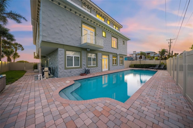 pool at dusk with a patio area