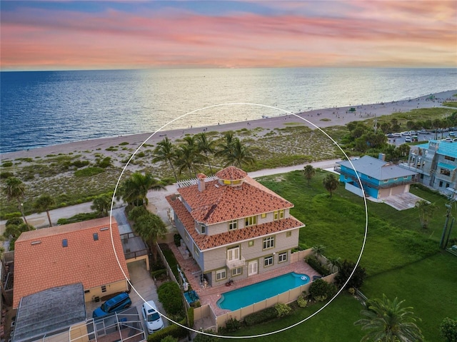 aerial view at dusk featuring a water view and a view of the beach