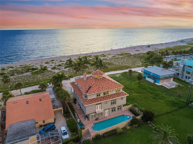 aerial view at dusk with a water view and a view of the beach