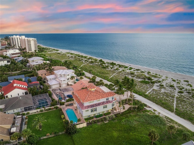 aerial view at dusk with a water view and a beach view