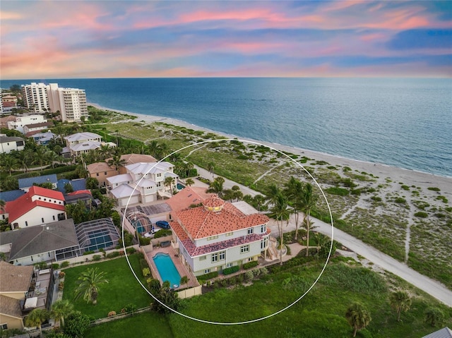 aerial view at dusk with a water view and a beach view