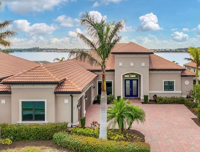 mediterranean / spanish-style home featuring a water view and french doors