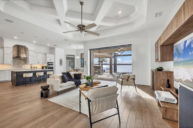 living room featuring light wood-type flooring, ceiling fan, ornamental molding, and coffered ceiling