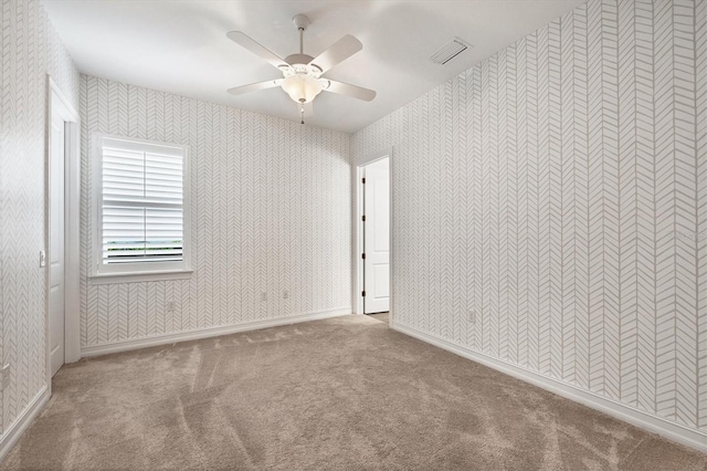 carpeted spare room with a ceiling fan, visible vents, and wallpapered walls