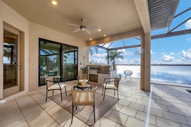 view of patio / terrace with a lanai, an outdoor kitchen, a ceiling fan, and area for grilling