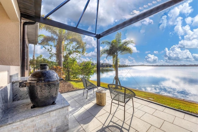 view of patio / terrace featuring glass enclosure, a water view, and grilling area