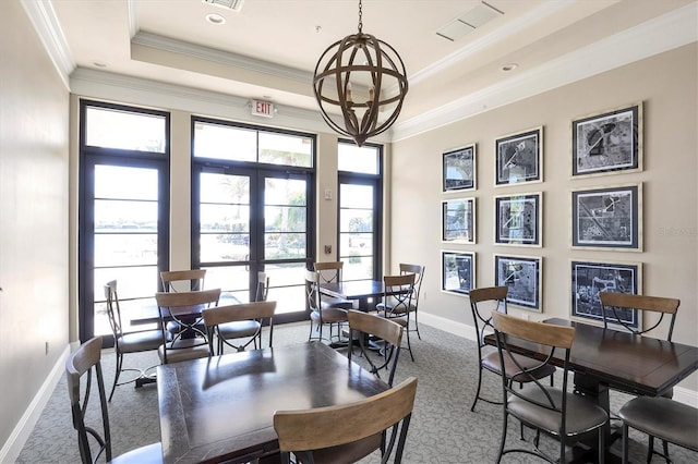 carpeted dining area with a raised ceiling, french doors, an inviting chandelier, and ornamental molding