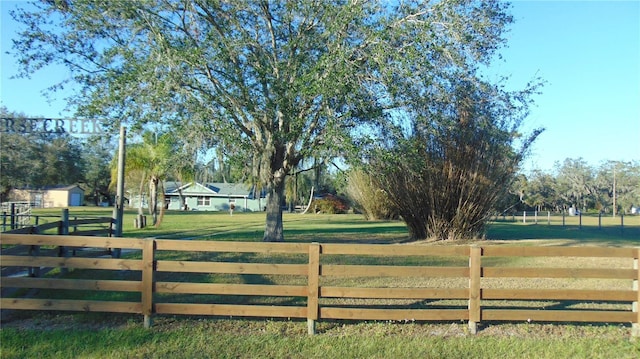 view of gate with a rural view and a lawn