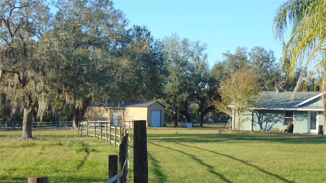 view of yard with a garage, an outbuilding, and a rural view