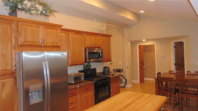 kitchen with appliances with stainless steel finishes and lofted ceiling